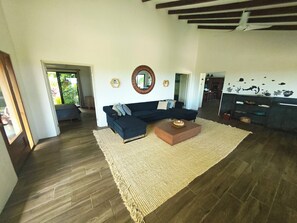Una sala de estar con un sofá modular oscuro, una mesa de centro de madera y un espejo grande en la pared.