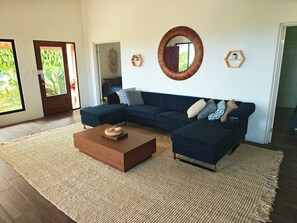 Una sala de estar con un sofá modular, una mesa de centro, un espejo redondo y un estante hexagonal.