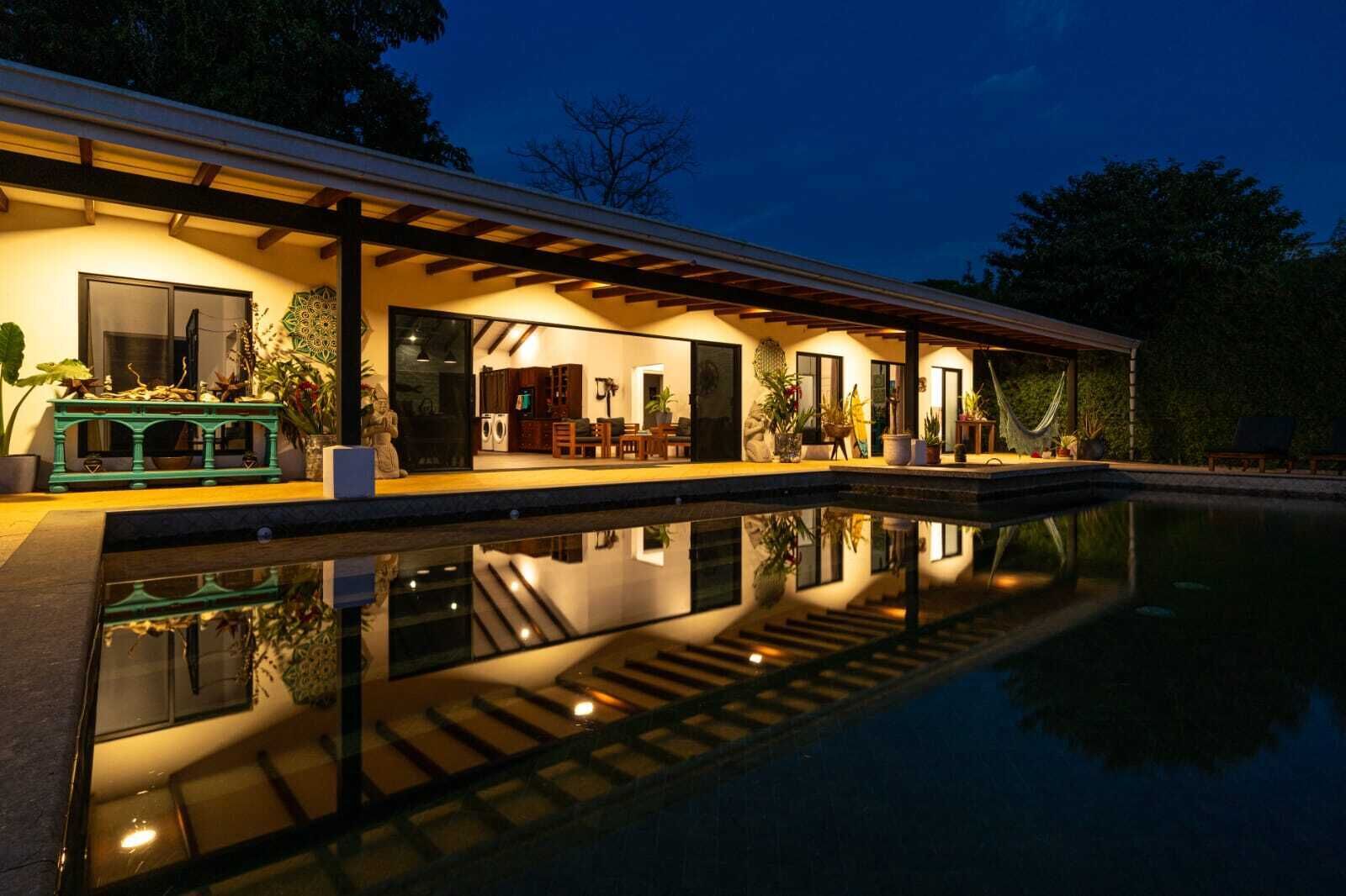 Une maison moderne dotée d’une piscine, d’un patio couvert et d’un intérieur bien éclairé.