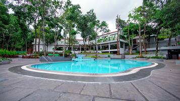 A swimming pool surrounded by trees and a building with a modern design.