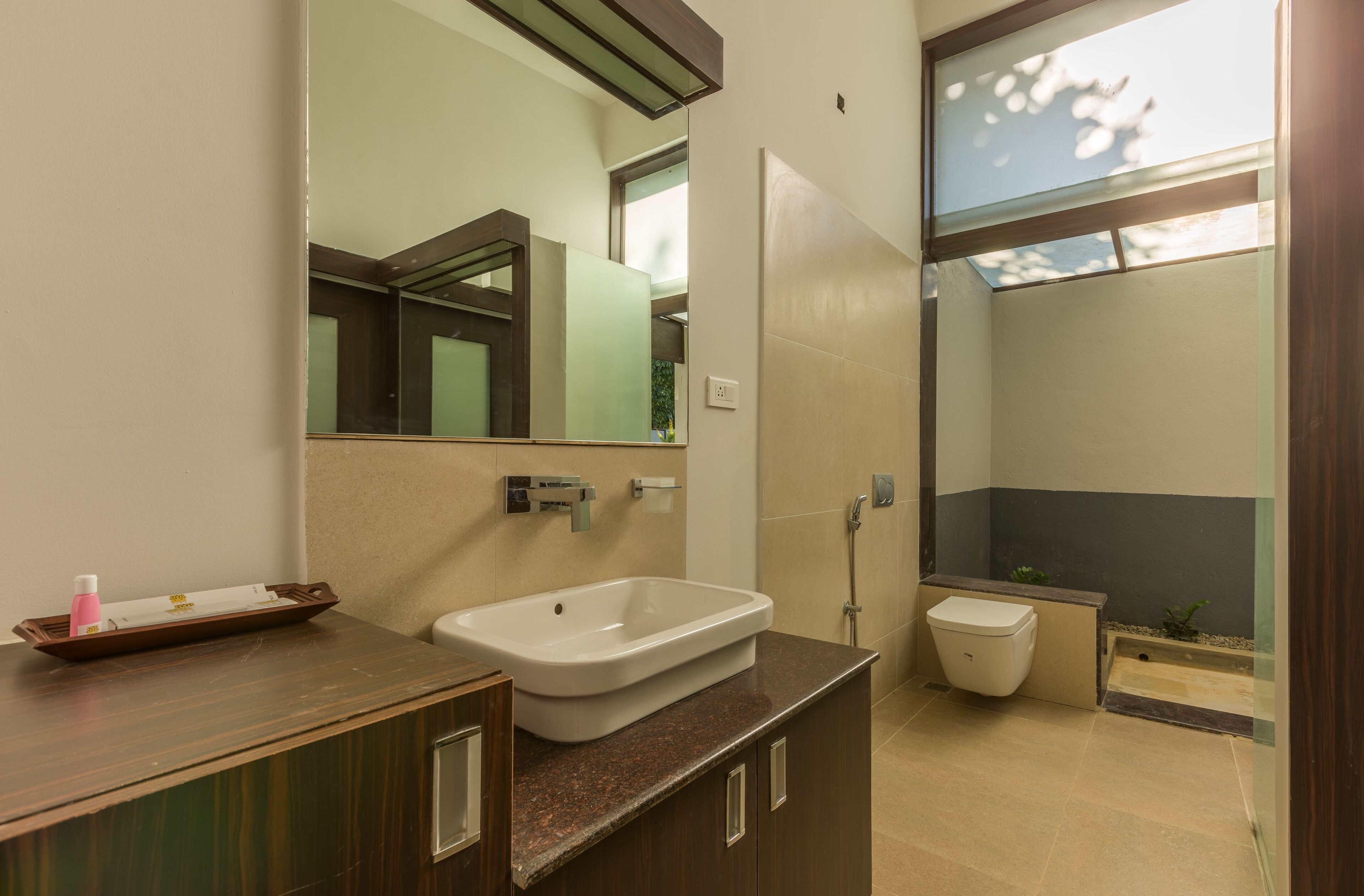 A modern bathroom with a large mirror, a sink, a toilet, and a shower area.