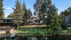 A residential area with a pond, trees, and outdoor seating. - Riverfront w/dock and big backyard. Enjoy your own slice of the Deschutes River. (Bend)