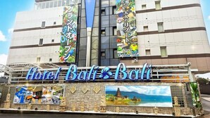 Un hôtel avec une enseigne bien visible portant l’inscription « Hôtel Bali Bali » et plusieurs banderoles colorées.