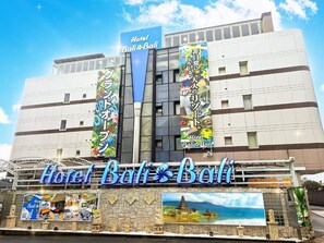 Um hotel com uma placa de destaque que diz 'Hotel Bali Bali' e várias bandeiras coloridas.
