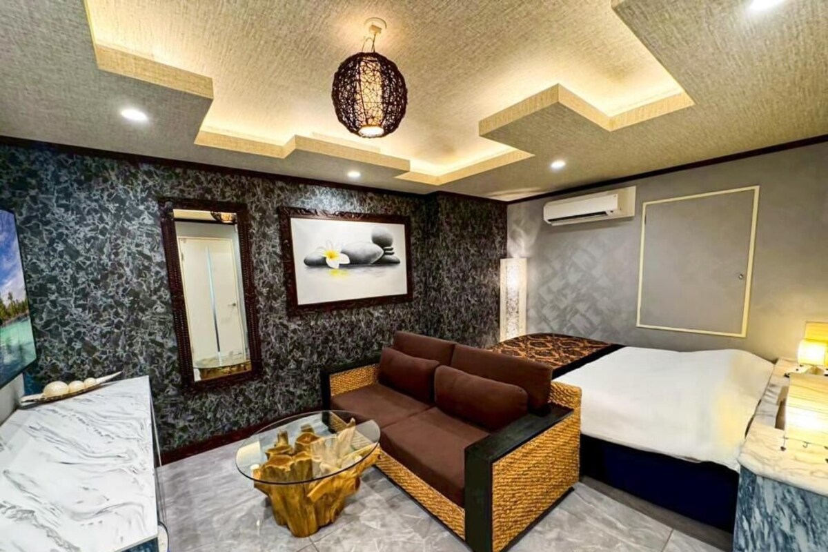 Quarto moderno com sofá, mesa de centro de vidro, cama e ar condicionado fixado na parede.