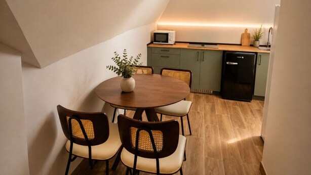 A dining area with a round table and four chairs, a small potted plant, and a kitchen in the background. - Madrid Pad With 2 Baths (Madrid)