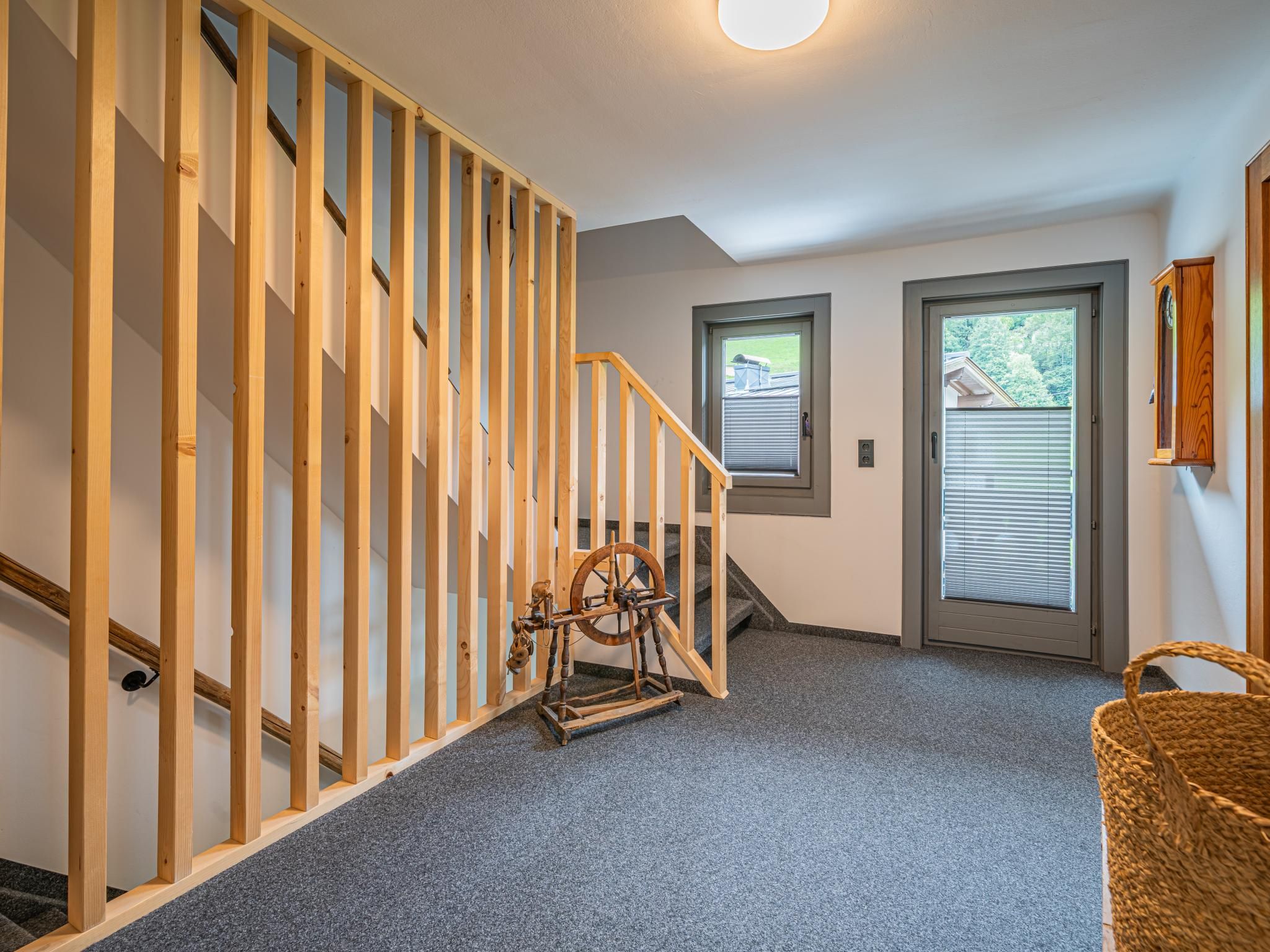 Un escalier avec des rampes en bois, un rouet et un panier posé sur le sol.