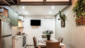 Een compacte keuken met een eethoek, een flatscreen televisie en een plant aan de muur.