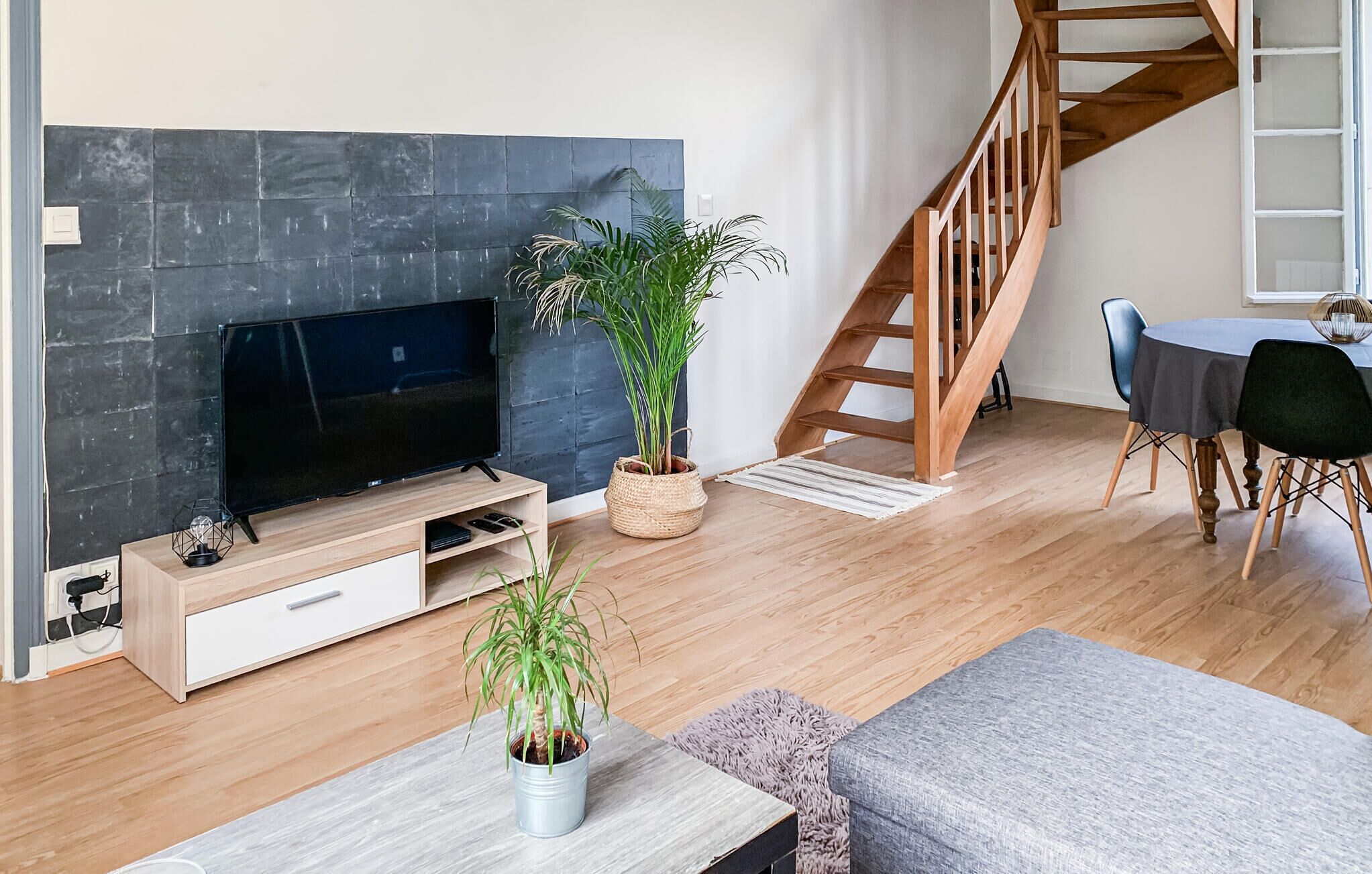 Un salon moderne doté d’un téléviseur à écran plat, de planchers en bois, d’un escalier et d’un coin repas.