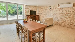 Un comedor con una mesa y sillas de madera, un televisor y una pared de piedra.