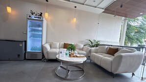 A modern lounge area with a seating arrangement, a refrigerator, and a view of the outdoors. - The Hotel Phoenix Inn (Indore)
