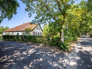 A residential property with a sloped roof, a white exterior, and a driveway leading to a gated entrance. - Cozy accommodation  near the beach and sea (Schoorl)
