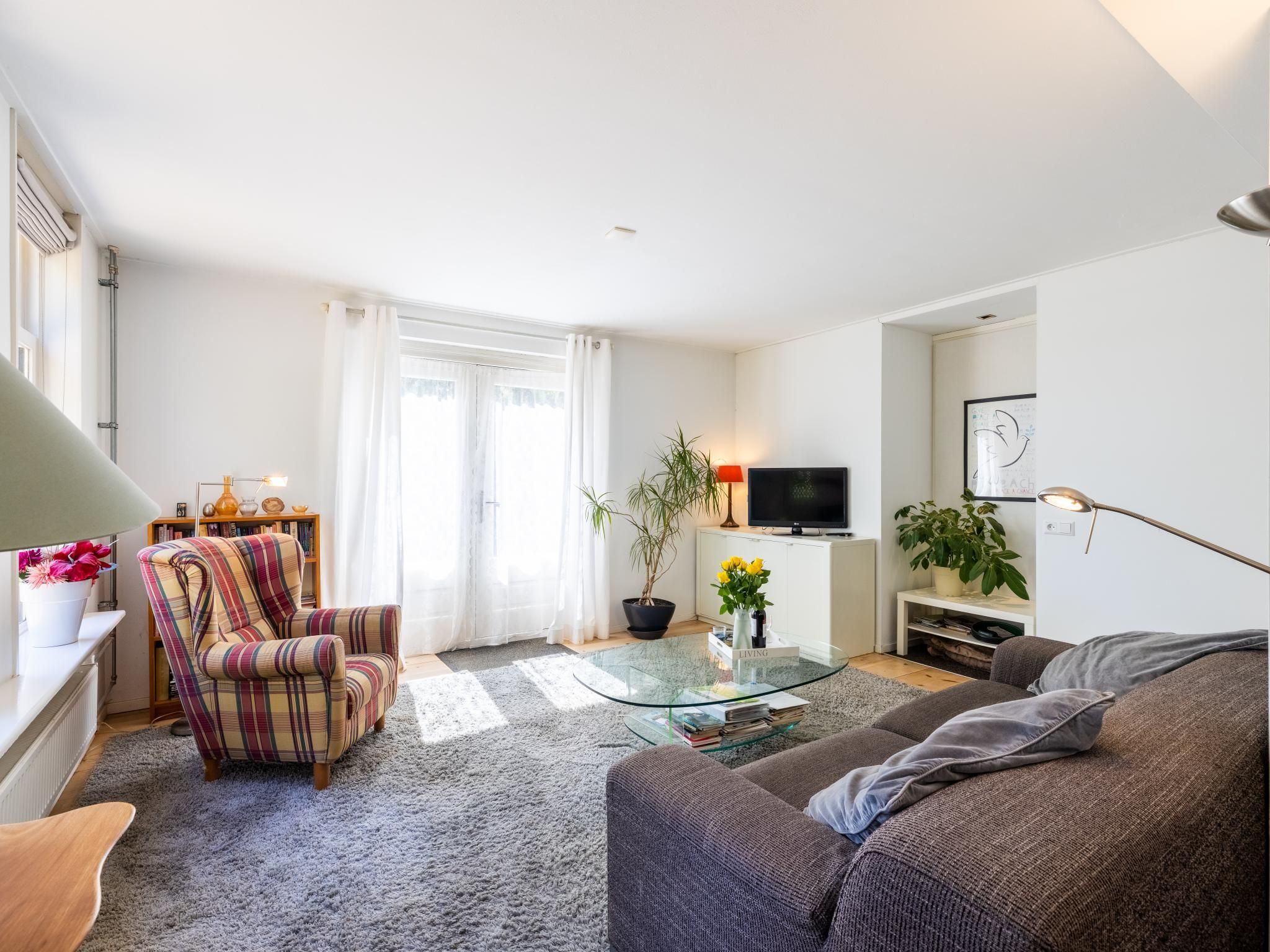 A modern living room with a sofa, armchair, and a glass coffee table.