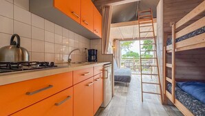 Eine kleine Küche mit orangefarbenen Schränken, einem Gasherd und einer Kaffeemaschine.