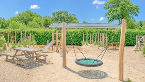 Ein Spielplatz mit Schaukel, Rutsche und Picknicktisch.