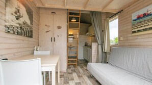 Et sommerhusinteriør med et tekøkken, spiseplads og en sofa.