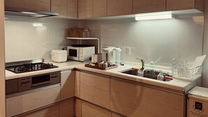 Una cucina compatta con piano cottura a gas, forno a microonde, tostapane e lavello con scolapiatti.