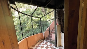 A room with a checkered floor, a window with a metal grid, and a view of greenery outside. - Backwoods B&B Mall Road Shimla (Shimla)