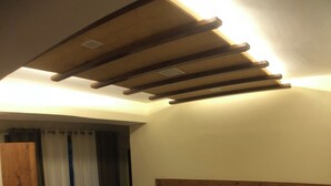 A bedroom with a wooden headboard, a bed with white linens, a small table, and a chair. - Backwoods B&B Mall Road Shimla (Shimla)