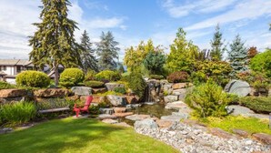 Ein angelegter Garten mit Teich, Steinen und einem roten Stuhl.