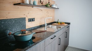 A kitchen with a granite countertop, a stove, a sink, and wooden cabinets.