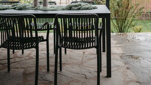 An outdoor patio with a table and chairs, a covered area, and a building in the background.