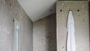 A bathroom with a shower, a towel rack, and a mirror.