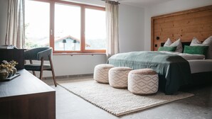 A bedroom with a bed, a desk, a chair, and a window with curtains.
