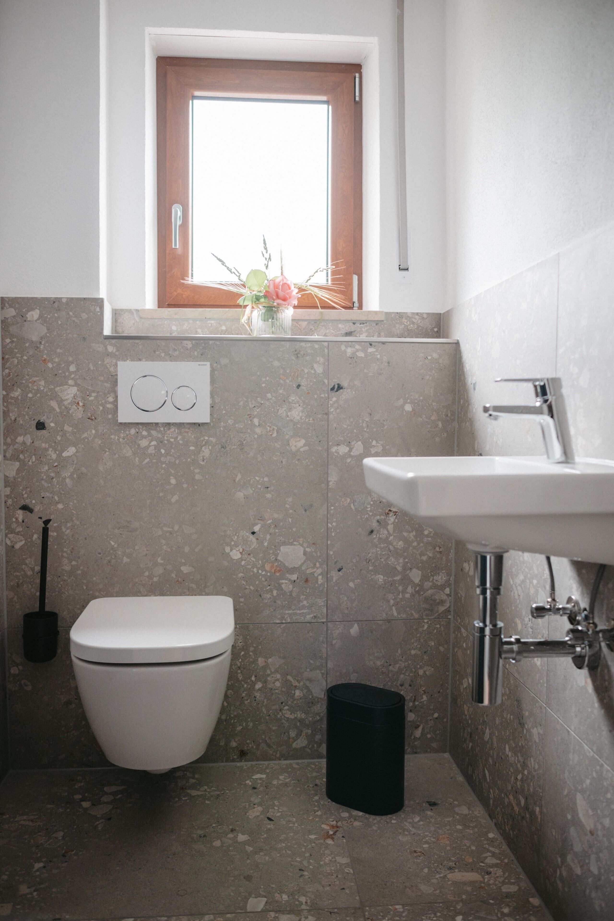 A bathroom with a toilet, sink, and window.