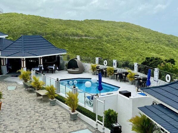 A rooftop pool area with a pool, lounge chairs, and tables. - BTS6 (Montego Bay)
