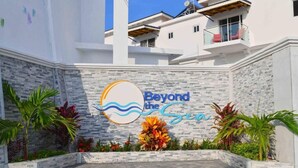 Un edificio con un cartel que dice 'Beyond the Sea' y un muro de piedra con plantas.