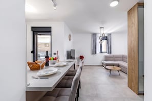 A modern dining area with a long table, chairs, and a sofa. - Zadar Family Residence (Zadar)
