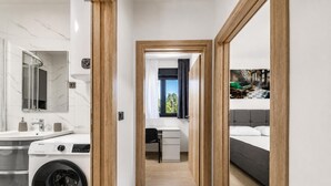 A modern hotel room with a washing machine, a desk, a bed, and a view of the outdoors. - Zadar Family Residence (Zadar)
