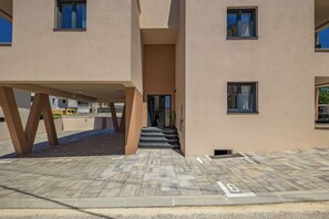 A modern building with a flat facade, a central entrance with steps, and a parking area marked with a number. - Zadar Family Residence (Zadar)