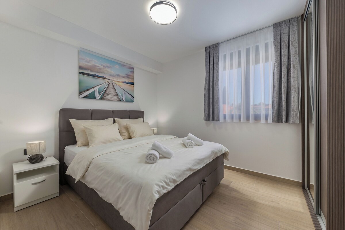 A modern bedroom with a bed, nightstand, and a painting on the wall.