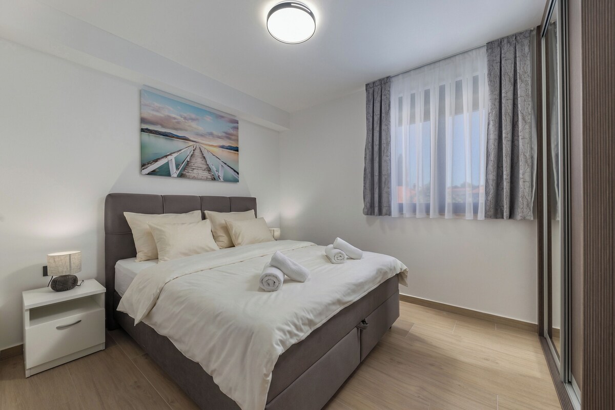 A modern bedroom with a bed, nightstand, and a painting on the wall.