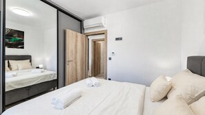 A modern hotel room with a bed, a mirror, an air conditioning unit, a door, and a wall-mounted light. - Zadar Family Residence (Zadar)