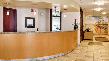 A reception desk with a wooden counter, a digital display, and a mural of a beach scene.
