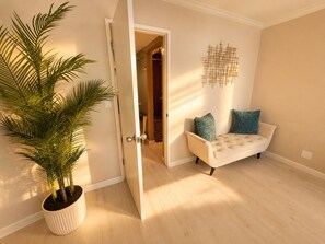 An open door leading to a hallway, a white sofa with teal cushions, and a potted plant. - Newly Renovated- LUXURY Oceanfront - High Floor with amazing Views! (San Diego)
