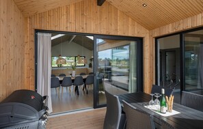 A modern dining area with a wooden ceiling, large sliding glass doors, and a view of the outdoors. - Beautiful home in Otterup with sauna (Otterup)