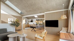Un salon moderne avec un canapé, une table basse et un coin repas, avec un téléviseur fixé au mur.