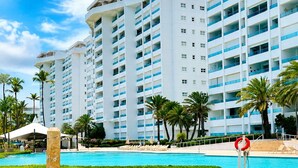 Un hotel con varios edificios altos, una piscina y palmeras.