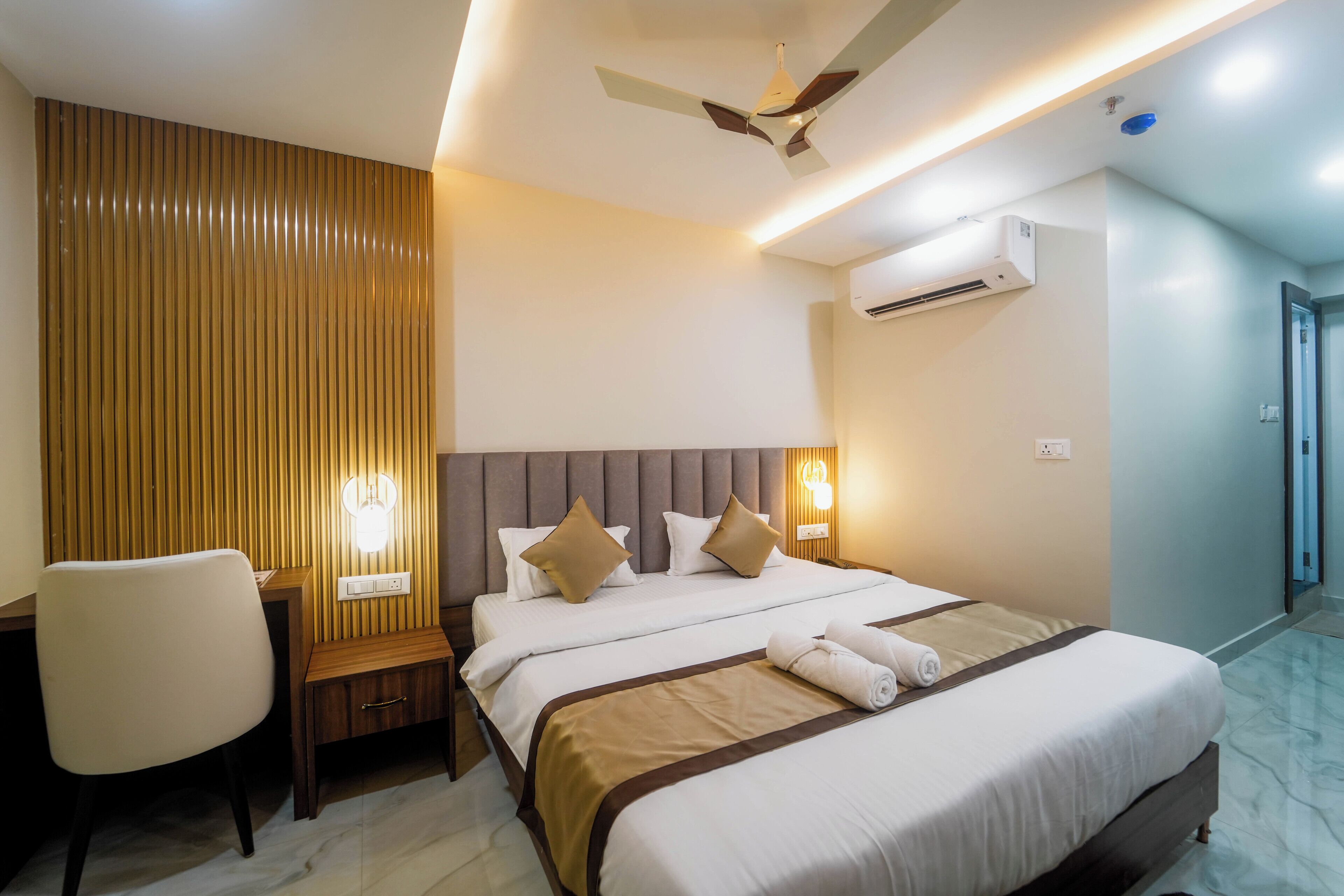 Ein Hotelzimmer mit Bett, Nachttisch, Stuhl und Klimaanlage.