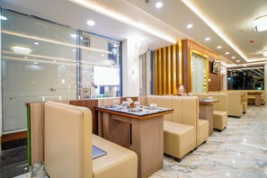 A restaurant with booths and tables, a television, and a marble floor. - Hotel Kanishka Inn (Varanasi)