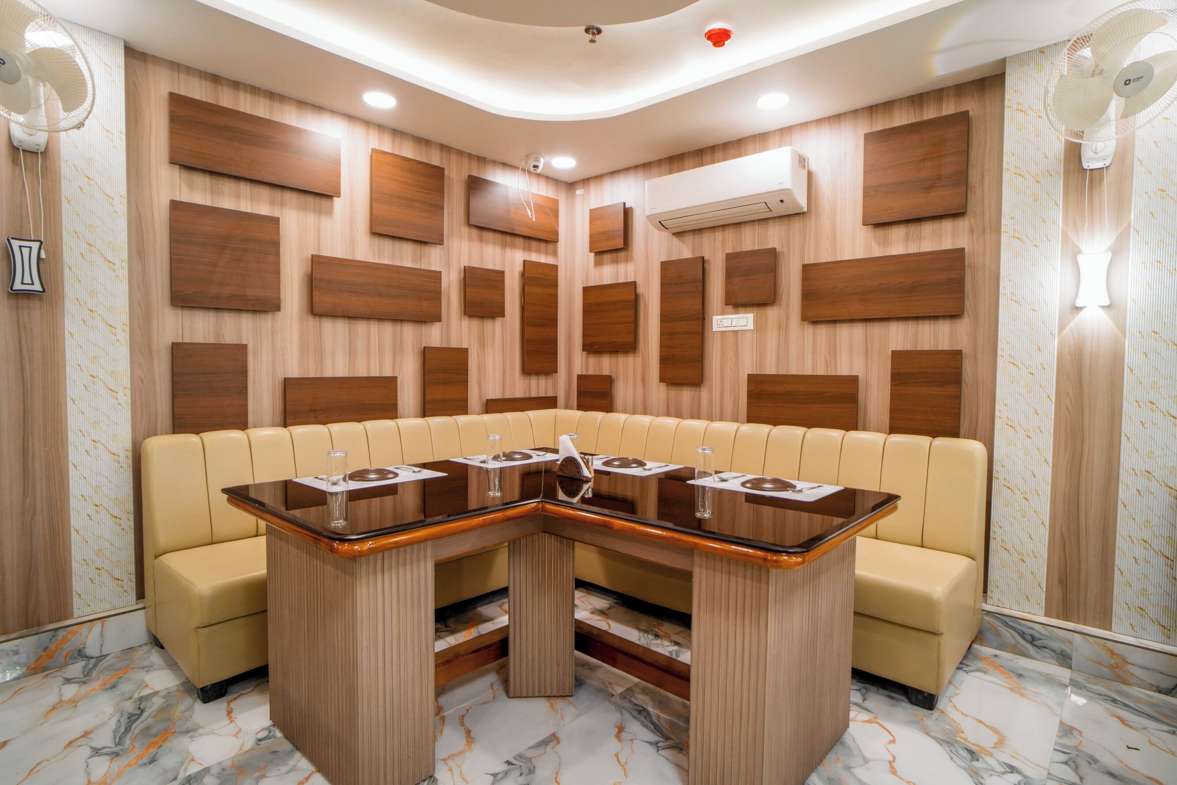 A corner seating area with a marble floor, wooden panel walls, and a central table with chairs.
