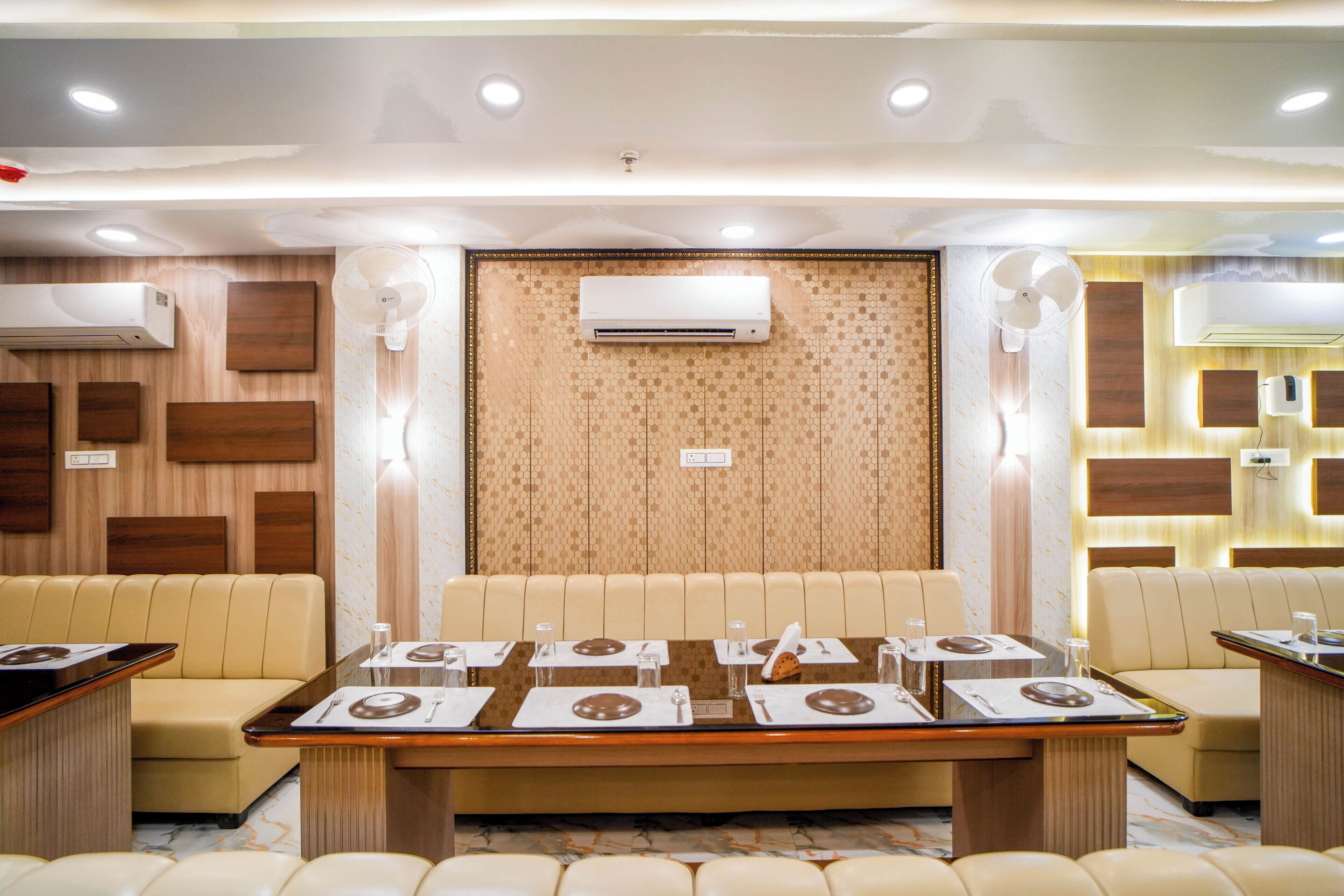 A hotel dining area with a long table set for multiple guests, surrounded by cushioned seating.