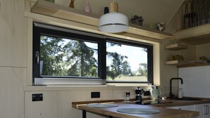 A compact kitchen with a window, two bar stools, and a coffee maker.