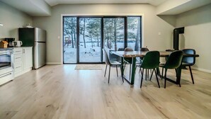 Une cuisine moderne avec un coin repas, de grandes portes-fenêtres coulissantes et une vue sur un paysage enneigé.