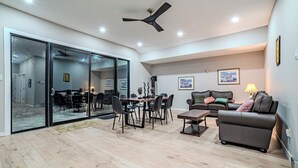 Un vaste espace de vie comprenant une table à manger, des chaises, un canapé et un ventilateur de plafond.