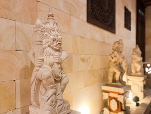 A stone sculpture of a deity with intricate carvings, set against a tiled wall in a temple or historical building. - Hotel Asian Resort (Sendai)